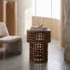 Minimalist living room with a lattice wooden side table, stacked design books, and a white sculptural ornament.