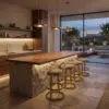 Modern kitchen with a wooden island, stone base, and brass bar stools under warm pendant lighting; large glass doors open to an evening patio.