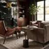 Cozy living room corner with a black marble fireplace, wooden bookshelves, and a large leafy plant by a window.