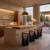 Modern kitchen with a marble island, wood cabinets, brass bar stools, and warm pendant lighting at dusk.