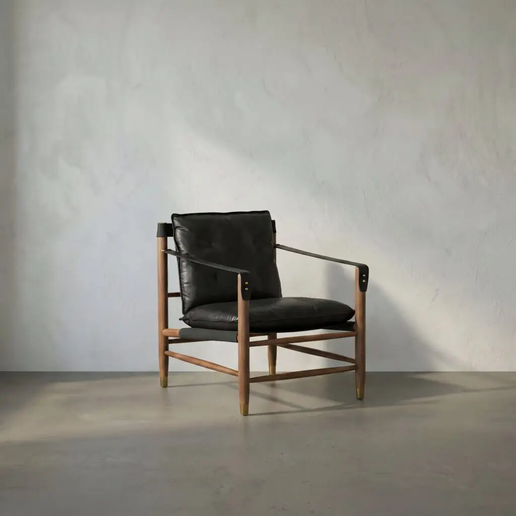Modern black leather lounge chair with wooden arms and legs placed in a sparse room against a textured light wall.