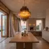 Luxurious dining area with a hanging glass chandelier, stone walls, and a sea view from the windows.