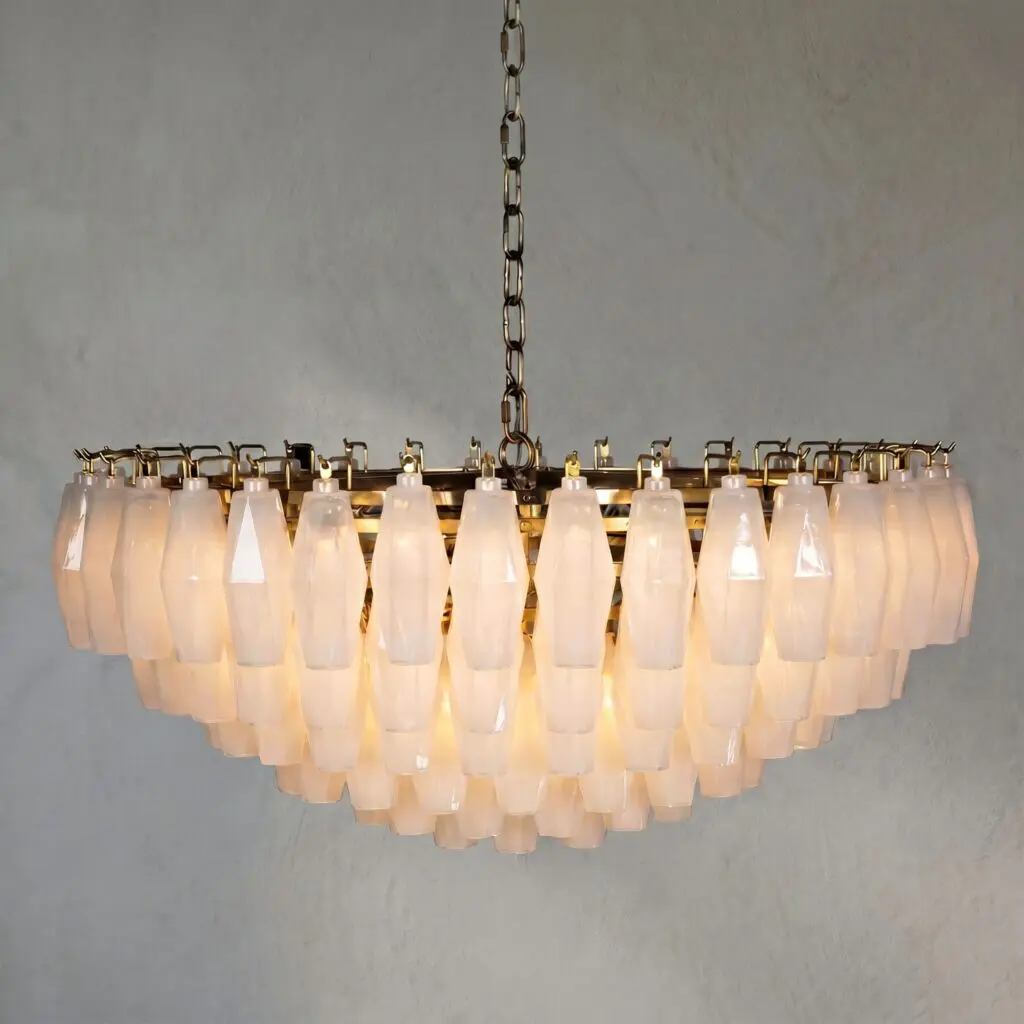 Chandelier with many frosted glass shades hanging from a metal chain against a gray wall.