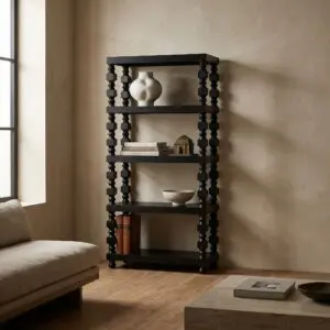 Tall black decorative bookshelf in a corner holding a white ceramic vase, small house figurines, and a stack of books against a beige textured wall near a window.