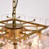 Close-up of a gold chandelier with a central hub and glass rectangular prisms hanging around it