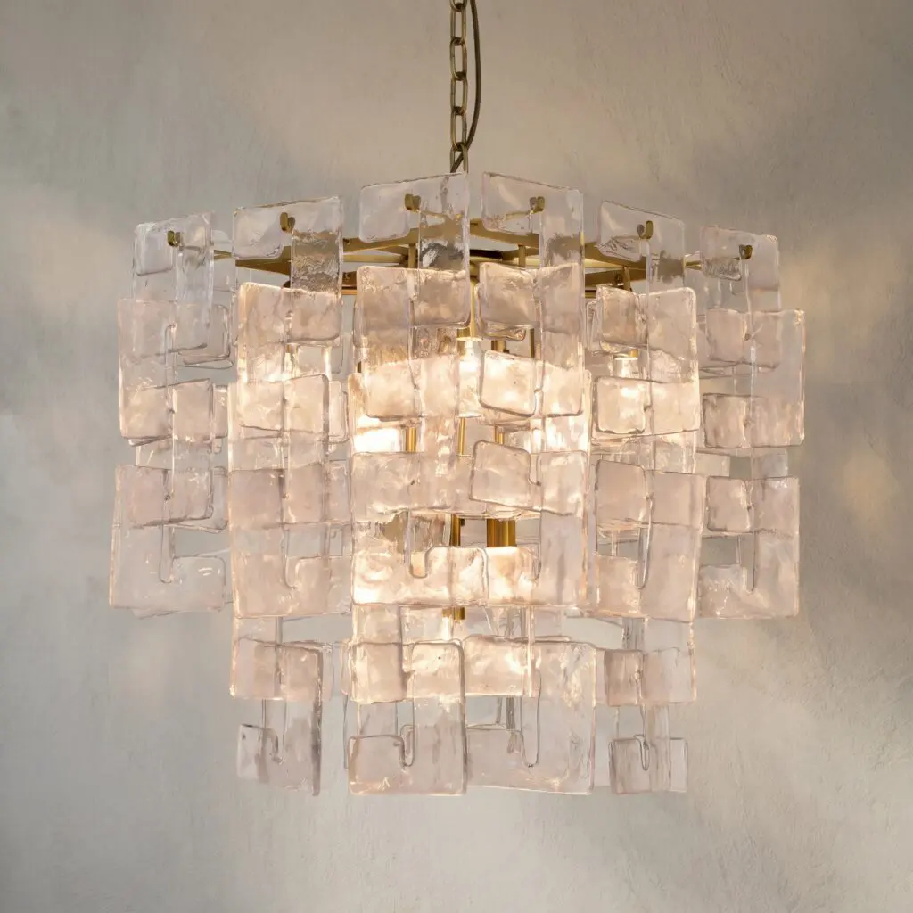 Crystal chandelier with square glass panels hanging from a brass chain, lit warmly.