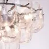 Close-up of a glass bubble chandelier with overlapping translucent panes and small black pins along the edges.