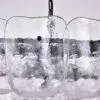 Close-up of clear ice blocks suspended in a row by a chain against a light background, forming a decorative sculpture.