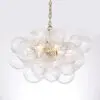 Cluster chandelier made of clear ribbed glass balls hanging from a brass chain and lit from inside