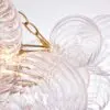Close-up of clear glass orbs with spiral textures connected by a gold chain, softly illuminated by warm lights