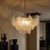 Elegant chandelier with frosted glass lampshades hanging from a metal chain in a warmly lit interior.