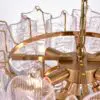 Close-up of a gold-toned chandelier with clear crystal prisms and curved metal arms.