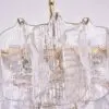 Close-up of a crystal glass chandelier with gold hanging hardware and vertical ridges on the prisms