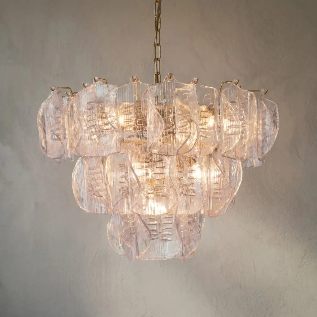 Crystal chandelier hanging from a metal chain, lit with a warm glow in the room light.