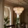 Elegant living room corner with ornate ceiling moldings, beige drapes, and a hanging glass chandelier.