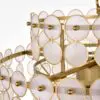 Gold-toned metal sculpture with multiple circular white discs arranged on rings (decorative chandelier-style structure).