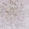 Crystal chandelier with overlapping frosted glass rectangles suspended by a brass chain and frame.