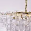Close-up of a gold chandelier with rectangular ice-like glass prisms hanging from chains.