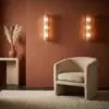 Warm-toned living room corner with two glass bubble wall sconces, a beige armchair, and a pampas grass vase on a white table.