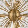 Close-up of a gold starburst chandelier with multiple exposed bulbs, radiating from a central hub.