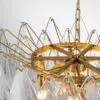 Close-up of a gold metal chandelier frame with hanging crystal prisms and rings centerpiece.