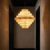 Warm alabaster pendant light with stacked circular rings hanging in a dark hallway.