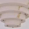 Close-up of a white marble spiral column with small gold knobs, part of a modern chandelier fixture.