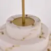 Close-up of a marble-textured cake with a vertical gold rod center and small gold knobs around the top edge.