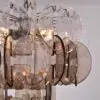 Close-up of a glass pendant chandelier with overlapping textured oval discs and metal chains