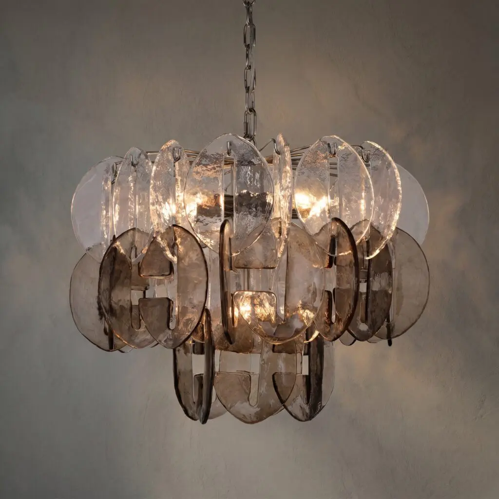 A modern chandelier hanging from a chain made of metal links, with numerous clear glass or translucent circular discs reflecting light.