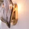 Close-up of a gold wall sconce with curved glass panels emitting warm light.