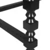 Close-up of a black metal decorative baluster with square and rounded segments, part of a railing assembly.