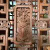 Intricately carved wooden lattice panel with blooming flowers and a shield-like emblem in the center.