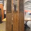 Three tall carved wooden screen panels with geometric lattice patterns and carved reliefs at the bottom, standing in a warehouse.