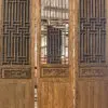 Three tall carved wooden screen panels with geometric lattice patterns and decorative reliefs, standing in a workshop.