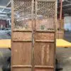 Pair of tall wooden lattice screen panels with geometric geometric fretwork, likely room dividers in an industrial warehouse setting.