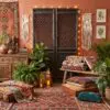 Bohemian-inspired room with layered patterned rugs, plants, and macrame wall hangings around a dark wooden cabinet.