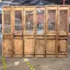 Row of tall rustic wooden room dividers with lattice panel fronts in an industrial warehouse setting