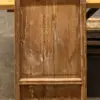 Front view of a weathered wooden cabinet door with a raised frame, worn brown finish, and visible grain patterns.