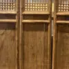 Wooden folding doors with vertical slats and lattice panels, set on a concrete floor.