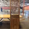 Tall wooden antique screen with an intricate geometric lattice, placed on a table in a warehouse with brick walls behind it.