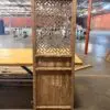 Tall, weathered wooden cabinet with a woven lattice front, standing on a pallet in a large, empty warehouse.
