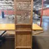Tall rustic wooden cabinet with lattice door inside a large warehouse/industrial space.