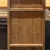 Rustic wooden cabinet with a lattice panel at the top and three vertical plank panels on the lower section, standing on a concrete floor.