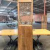 Tall wooden room divider with intricate geometric lattice panels, standing on a table in an industrial warehouse setting