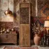 Rustic interior scene with a large copper pendant lamp, wooden cabinet, and colorful woven rugs leaning on the wall, creating a warm vintage display.