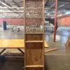 Tall wooden lattice screen with woven pattern on a platform inside an empty warehouse.
