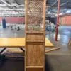 Tall antique wooden cabinet with a decorative lattice front panel in an empty warehouse setting.