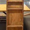 Tall wooden cabinet with a lacy lattice upper panel, three boxed sections, and a solid lower panel, placed in a workshop setting.