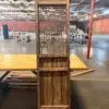 Tall rustic wooden room divider with geometric lattice panels standing on a wooden pallet in a spacious industrial warehouse.